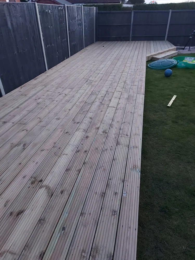 A large wooden deck in a backyard.