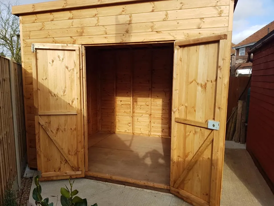 A large wooden shed with a door open.