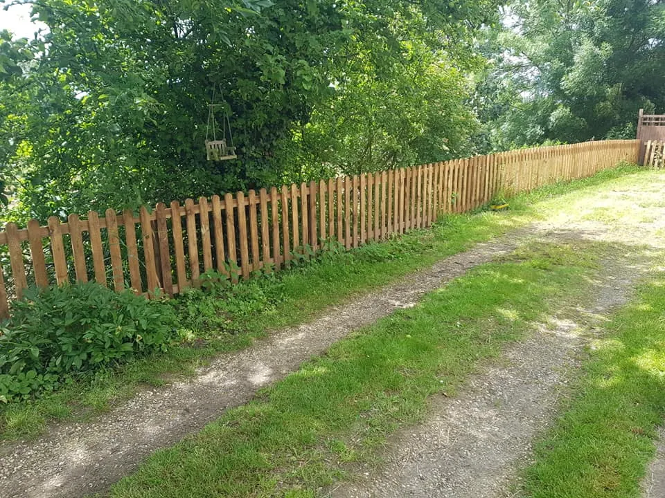 A wooden fence next to a dirt road.