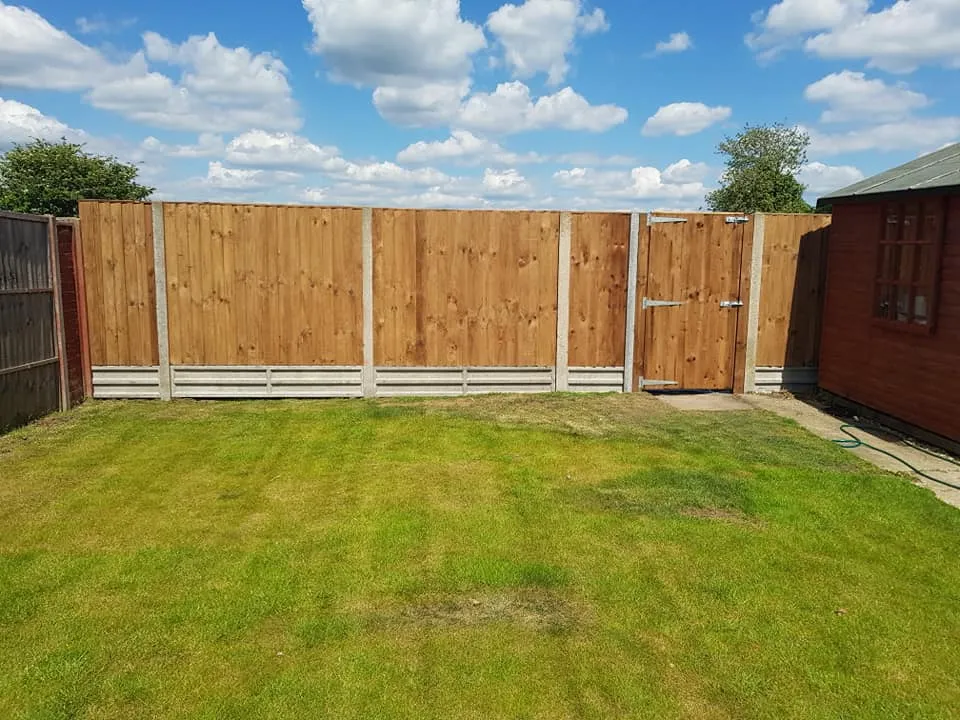 A yard with a fence and a green lawn.